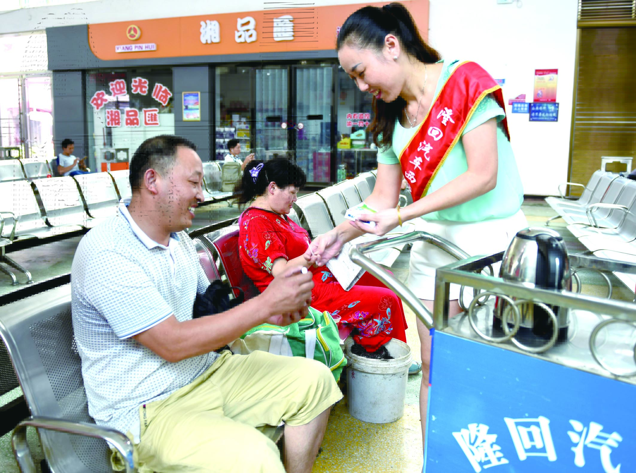 隆回分公司汽車西站工作人員正在為旅客免費贈送藿香正氣水。